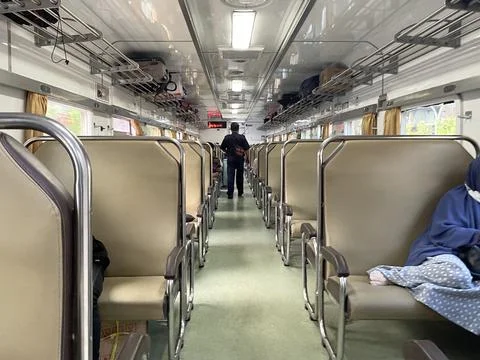 Economy class train interior with two rows of seats with passengers sitting Stock Photos