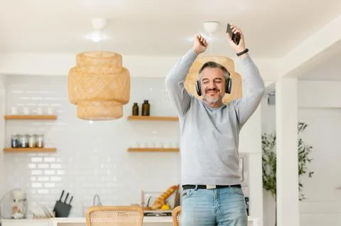 Ecstatic excited grey-haired man wear wireless headphones enjoy music. Stock Photos