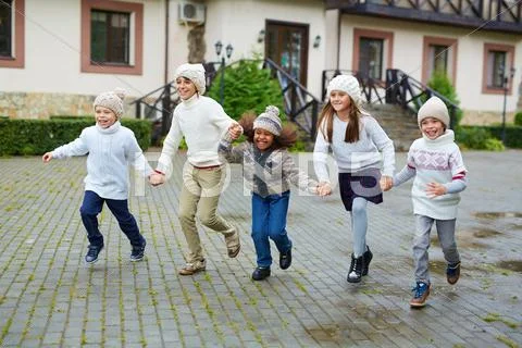 Ecstatic kids running down wet road Stock Photos