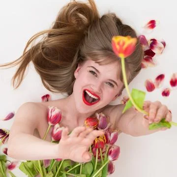 Ecstatic lady is posing with tulips for Woman's Day, with flowers nestled o.. Foto stock