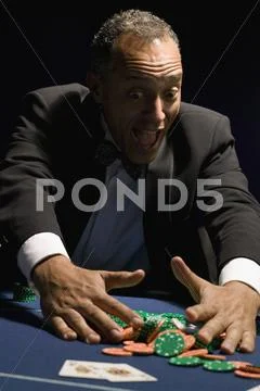 Ecstatic man gathering winning chips at casino table Stock Photos