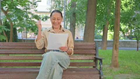 Ecstatic Multi Ethnic Woman with Documents on Park Bench 動画素材 310594445