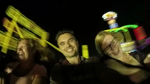 Ecstatic people having fun on rollercoaster ride in amusement park at night 库存影片 64513776