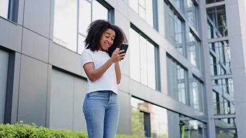 Ecstatic woman using smartphone and expressing positive emotions by building Stock-Footage 279964015