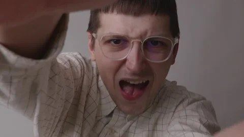 Ecstatic young man with glasses shouting joyfully looking at camera POV 스톡 동영상 335143487