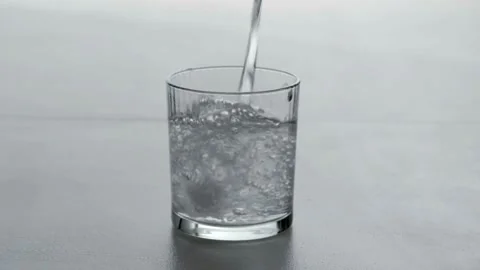 ECU TD SLO MO Shot of Water being poured into Glass against White Background Stock Footage 265844867