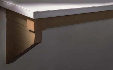 Edge and corner of table top made of white stone. Table top on wooden frame. Stock Photos