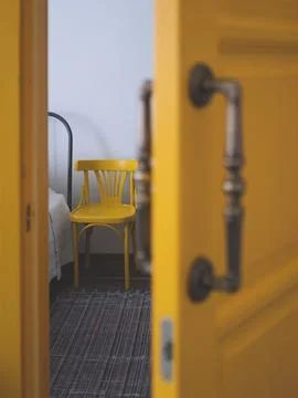 Edge of the bed and a next standing chair from half-open door Stock Photos