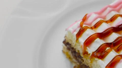 Edge of cake with cream and different jams on top, rotating in a white plate Stock Footage 54341354