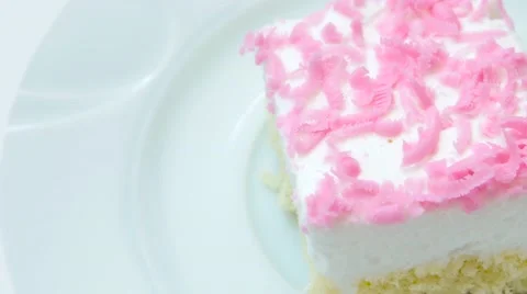 Edge of cake with pink decoration rotates on white plate Stock Footage 54228642