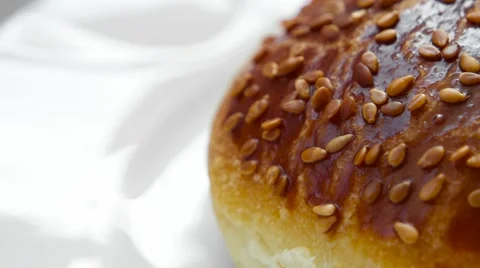 Edge of fresh baked bun with sesame seeds rotates on white plate Stock Footage 54337948