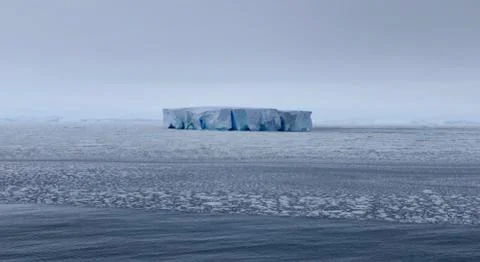 Edge of pack ice in antarctic ocean with large iceberg, Antarctica Stock Photos