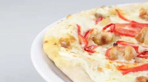 Edge of pizza with chicken and tomatoes rotates on the white plate Stock Footage 53580786