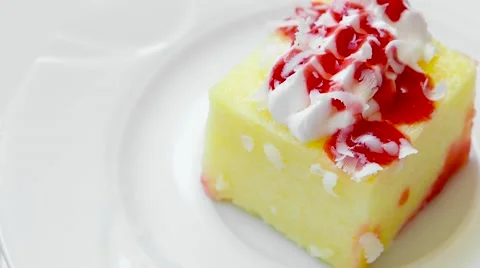 Edge of pudding with strawberry jam rotates on white plate, top view Stock Footage 54229581