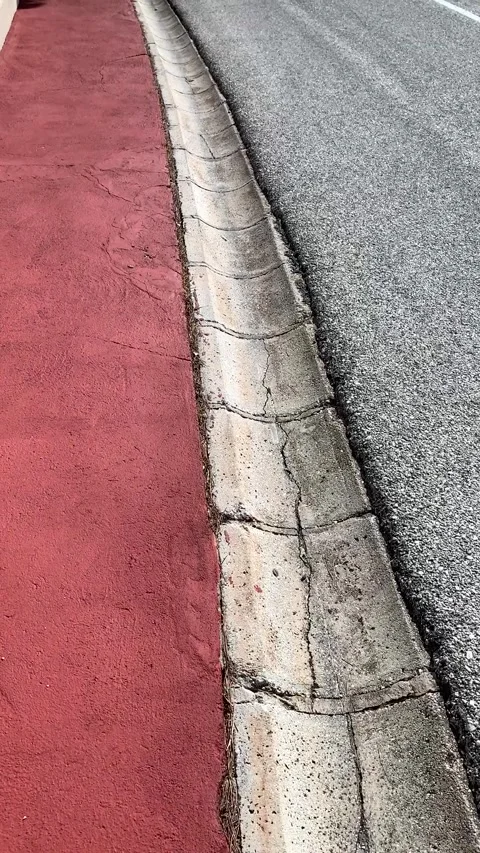 Edge of red Spanish sidewalk with a stone drainage channel Stock Footage 308306309