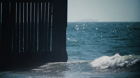 Edge of the US Mexico Border wall runs into Pacific Ocean, Imperial Beach, CA Stock Footage 114833538