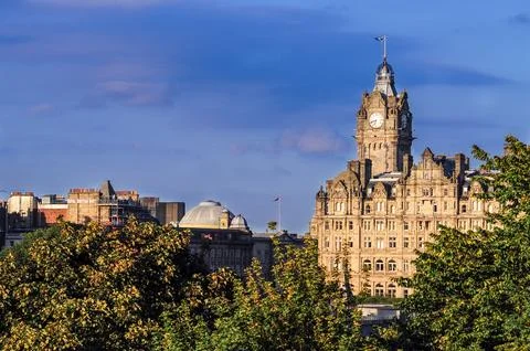 Edinburgh cityscape with clock tower at sunset amidst greenery Stock Photos
