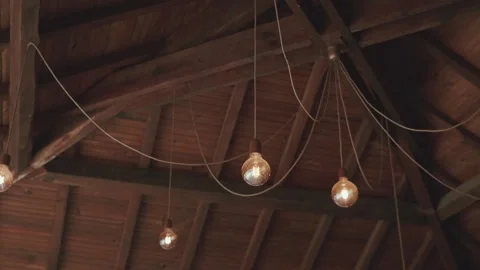Edison bulbs hanging from rustic wooden beam ceiling closeup Stock Footage 337780846