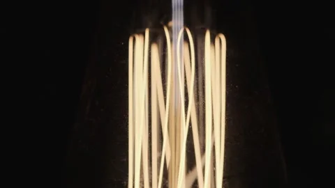 Edison lamp base on black background lights up close-up in slow motion Stock Footage 143540457