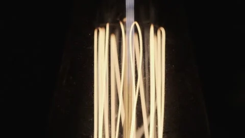 Edison lamp base on black background lights up close-up in slow motion Stock Footage 143540458