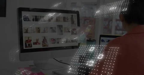 Editing Asian editor selecting portrait grid on office screen, wearing coral, Stock Photos