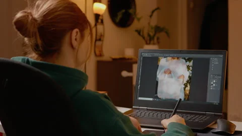 Editing images with graphics tablet in a cozy home studio setting at night Stock Footage 303691158