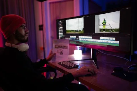 Editing video content in a modern workspace with colorful lighting at night Foto stock