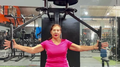Editorial: 70-Year-Old Senior Woman Training with Pec Deck Fly Machine at Gym Stock Footage 330803002