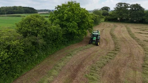 Editorial: Boundary tree line while a baling machine wraps haylage Stock Footage 294684991