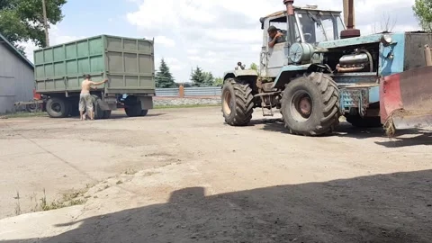 Editorial footage of tractor loading trailer on rural farm worksite Stock Footage 322902177