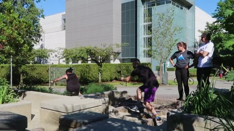 EDITORIAL. Freerunner flips over cement barrier while friend films Stock Footage 304777281