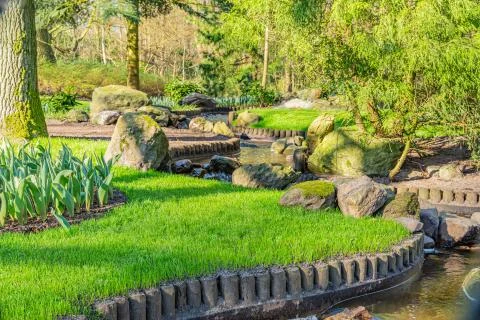 Editorial: Garden with a small artificial zig zag canal surrounded by trees Fotos Stock