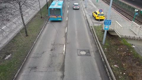 Editorial high-angle shot of a blue city bus and black car on a weathered road Vidéo 331286617