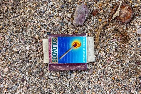 Editorial: Old and crushed Soldados matchbox thrown on wet sand of beach Stock Photos