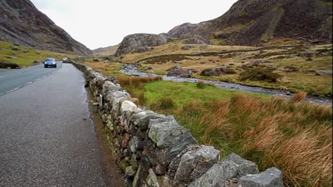Editorial, Road through Rugged Mountain pass with dry stone wall. stream behind. Stock Footage 205398524