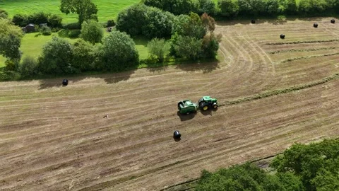 Editorial: Tractor baling machine combo surrounded by the plastic wrapped bales Stock Footage 294684988