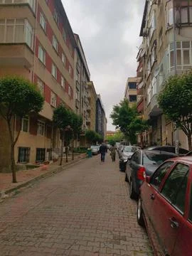 An editorial vertical perspective of a quiet, narrow residential street paved Stock Photos