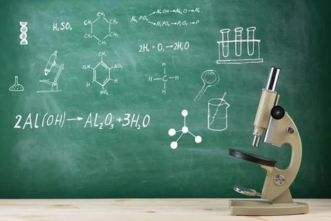 Education concept - microscope on the desk in the auditorium, blackboard back Foto stock