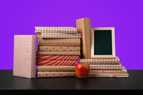 Education concept with stack of books on a table against colored background. Stock Photos