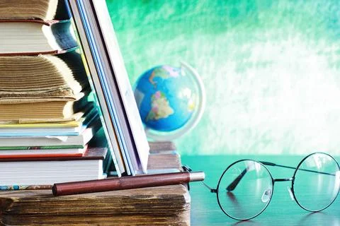 Education concept. A stack of textbooks and a book on the desk with glasses.. Stock Photos
