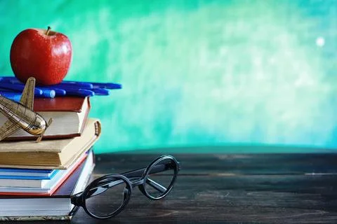 Education concept. A stack of textbooks and a book on the desk with glasses.. Stock Photos