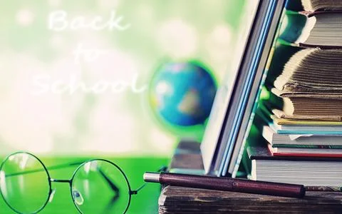 Education concept. A stack of textbooks and a book on the desk with glasses.. Stock Photos