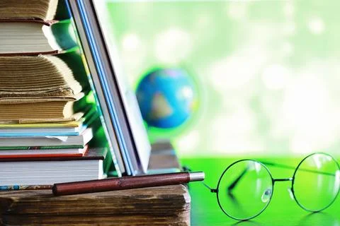 Education concept. A stack of textbooks and a book on the desk with glasses.. Stock Photos
