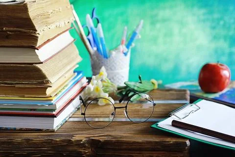 Education concept. A stack of textbooks and a book on the desk with glasses.. Stock Photos