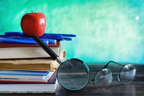 Education concept. A stack of textbooks and a book on the desk with glasses.. Stock Photos