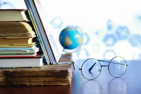 Education concept. A stack of textbooks and a book on the desk with glasses.. Stock Photos