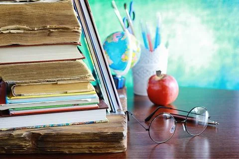 Education concept. A stack of textbooks and a book on the desk with glasses.. Stock Photos