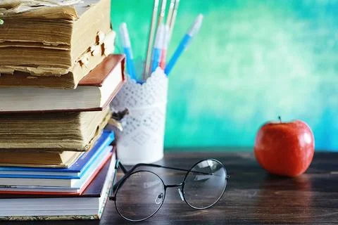 Education concept. A stack of textbooks and a book on the desk with glasses.. Stock Photos