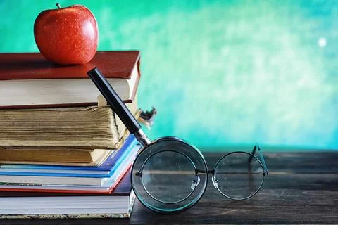 Education concept. A stack of textbooks and a book on the desk with glasses.. Stock Photos