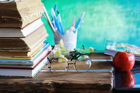 Education concept. A stack of textbooks and a book on the desk with glasses.. Stock Photos
